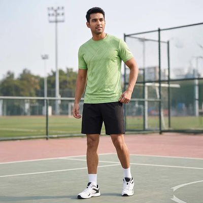 Man on an outdoor court wearing a light green round-neck jersey with diagonal line texture and black shorts