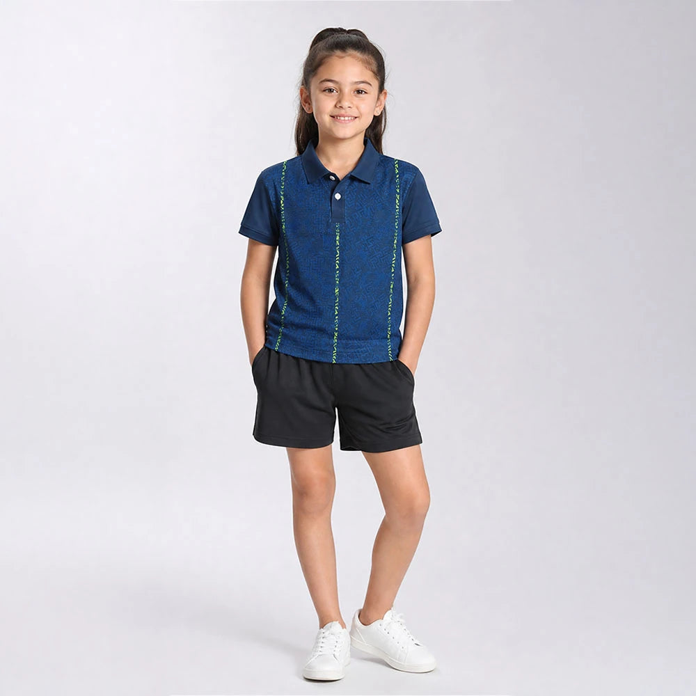 Child wearing the navy with fine neon vertical lines polo jersey with black shorts, standing in a studio.