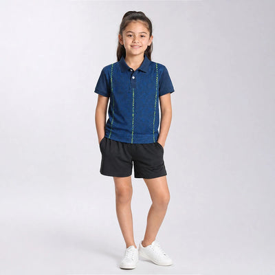 Child wearing the navy with fine neon vertical lines polo jersey with black shorts, standing in a studio.