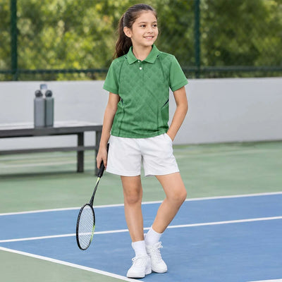 Child wearing a sage green with a small geometric pattern polo jersey and white shorts, holding a racket on court.