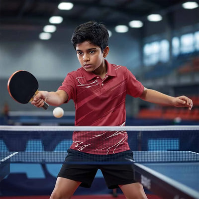 Child wearing the maroon with white angular accents polo jersey with black shorts, playing table tennis.